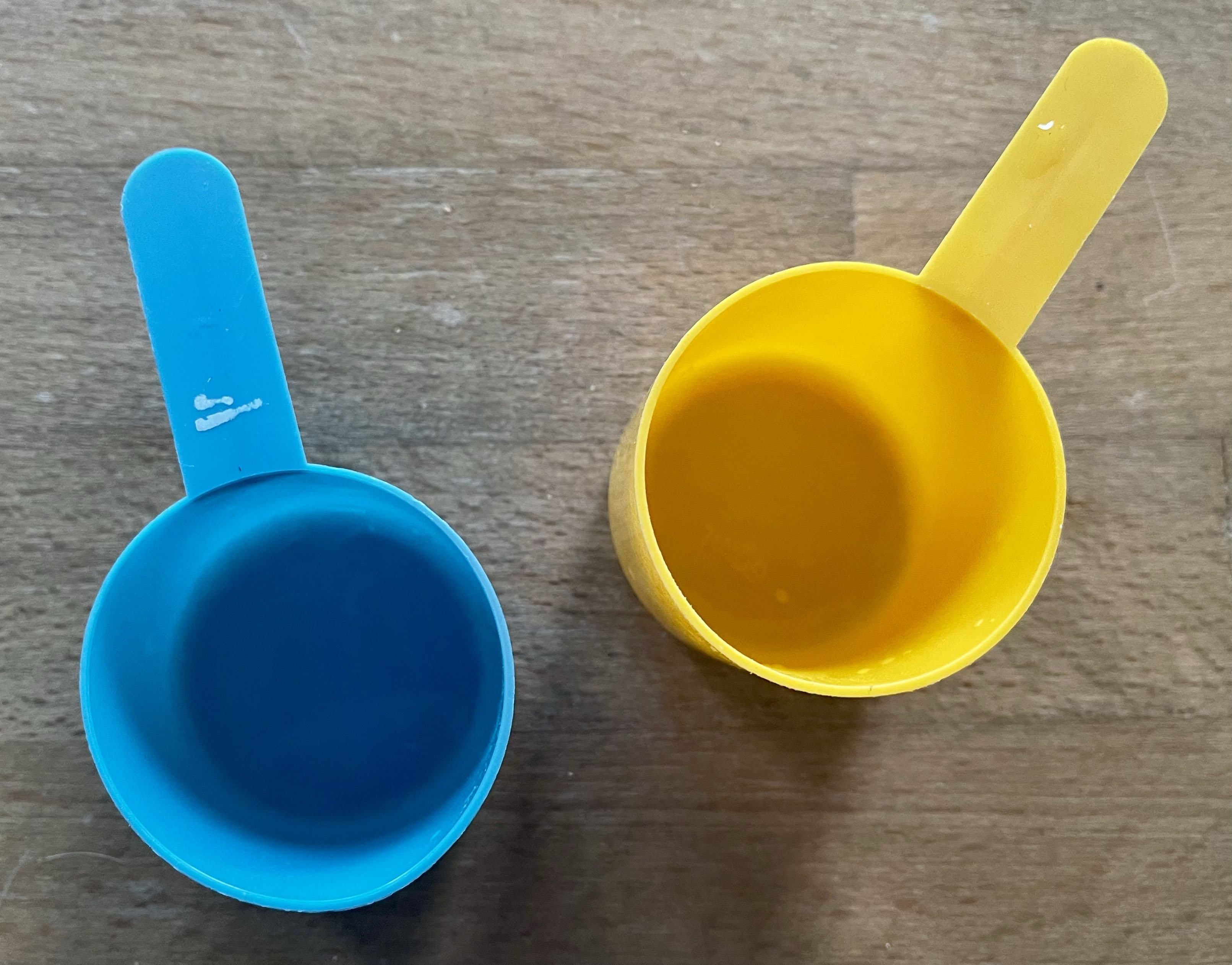 Photograph of two small plastic scoops, one blue, one yellow